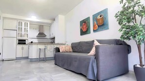 A modern living room with a grey sofa, a coffee table, and a potted plant. - Laguna Green Apartment (El Morche)