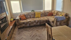 A cozy living area with a sofa, a small table, and a television. - Seaside Escape at Nab Tower Lane (Chichester)
