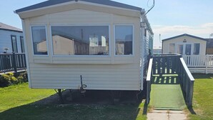 A mobile home with a front porch and a small ramp leading to the entrance. - Seaside Escape at Nab Tower Lane (Chichester)