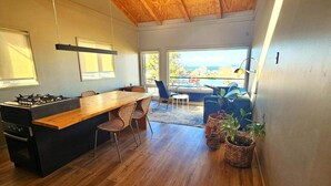 A modern kitchen with a wooden island, built-in gas stove, and a dining area with wicker chairs.