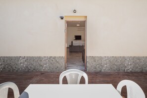 Une chambre d’hôtel avec un sol carrelé, un lit équipé d’un téléviseur et une porte donnant sur une autre pièce.
