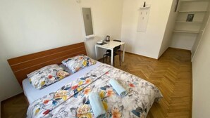 A bedroom with a bed, a desk, and a chair.