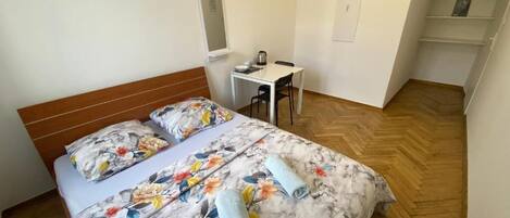 A bedroom with a bed, a desk, and a chair.