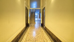 Ein Flur mit Marmorboden, einer Treppe und Türen an beiden Seiten.