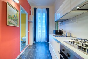 A narrow kitchen with a gas stove, a microwave, and a sink.
