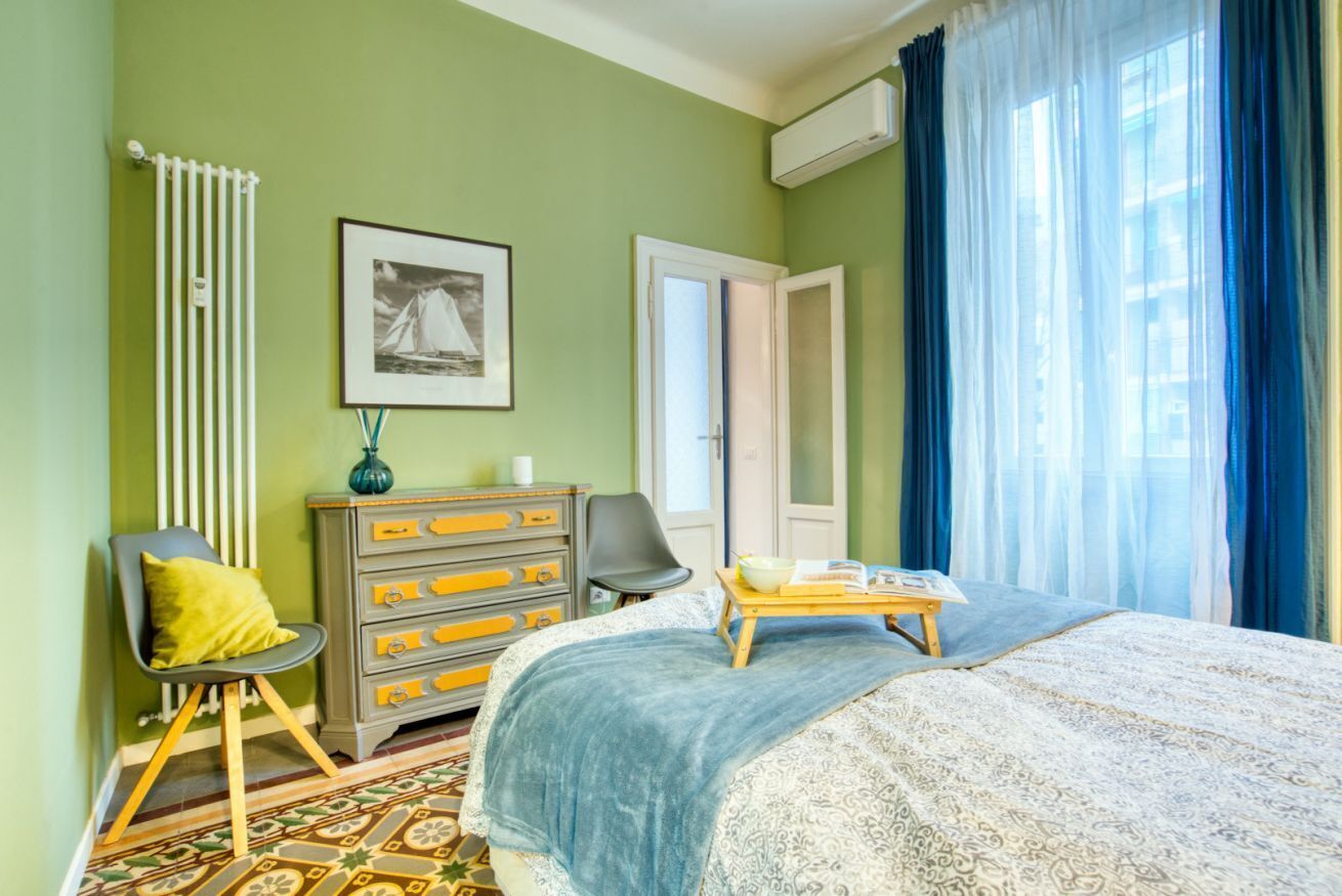 A bedroom with a bed, dresser, chair, and a window with curtains.