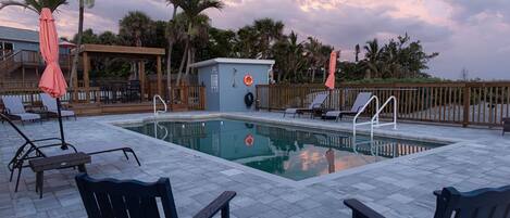 A pool area with lounge chairs, a small pool, and a wooden deck.
