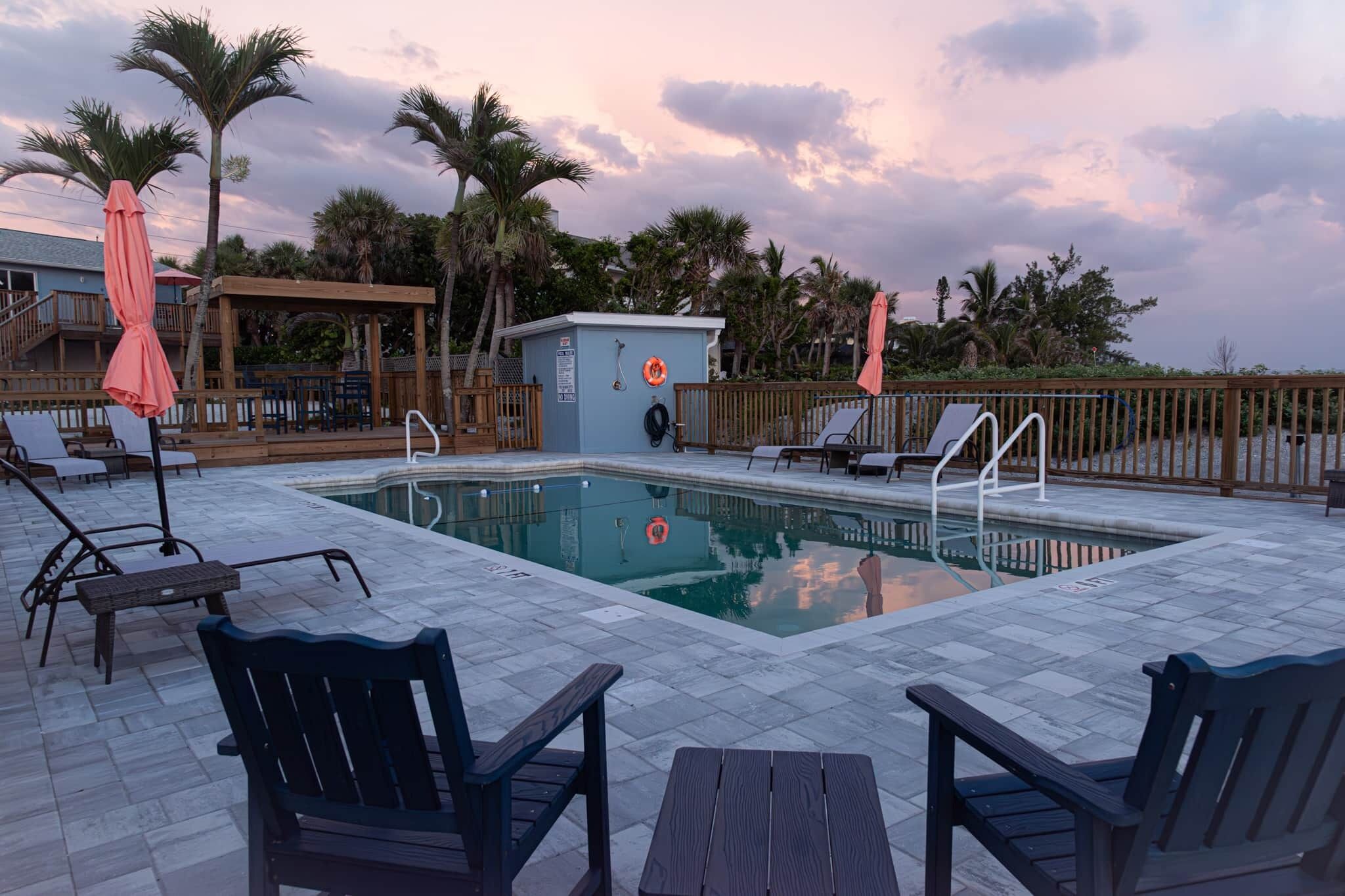 A pool area with lounge chairs, a small pool, and a wooden deck.