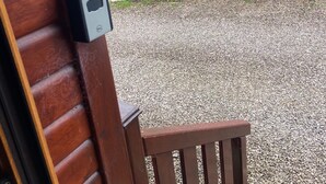 A wooden bench with a stone wall and gravel in the background. - Kingfisher Cosy Lakeside Lodge (Carnforth)