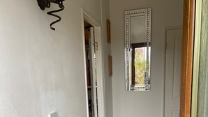 A hallway with a radiator, a light fixture, and a mirror on the wall. - Kingfisher Cosy Lakeside Lodge (Carnforth)