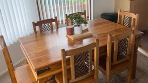 A dining area with a wooden table and chairs, a potted plant, and a kitchen with a microwave. - Kingfisher Cosy Lakeside Lodge (Carnforth)