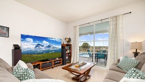 Uma sala de estar com uma grande televisão de tela plana, uma mesa de centro de madeira e um sofá.