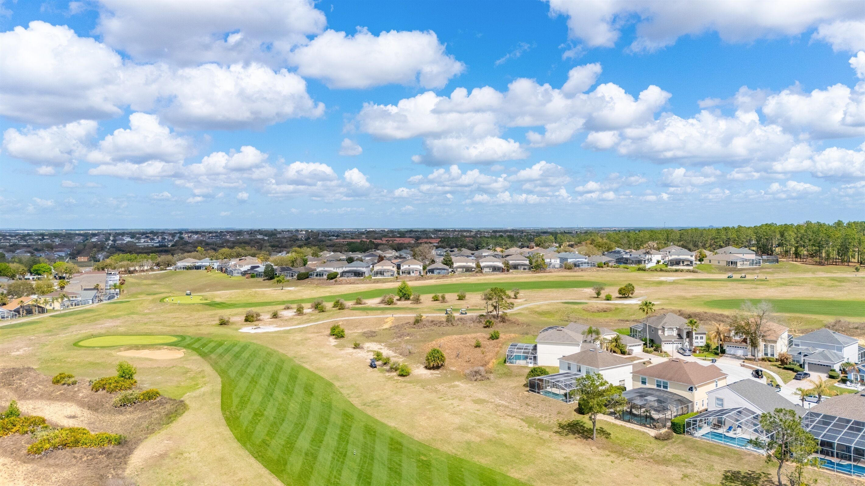 Un quartiere residenziale con case, un campo da golf e cielo sereno.