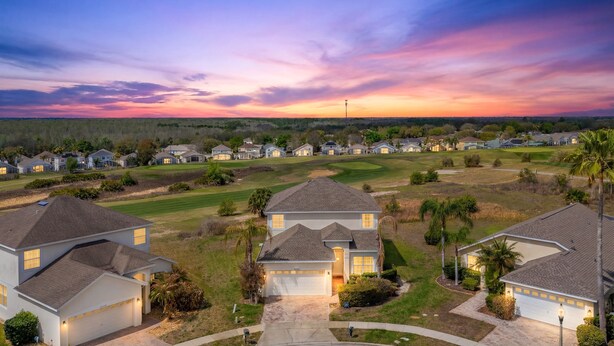 Zona residencial com casas, campo de golfe e céu ao pôr do sol.