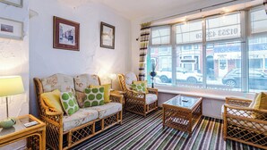 A cozy room with a sofa, chairs, a table, and a window with a view of the street. - Blackpool Lodge Double Room (Blackpool)