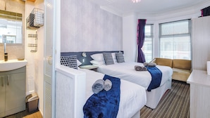 Ett hotellrum med två sängar, ett badrum och ett fönster med gardiner.
