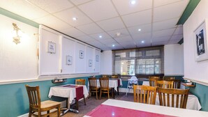 A dining area with tables and chairs, a wall-mounted light fixture, and framed pictures on the wall. - Double Room 2nd Floor Room 5 (Blackpool)