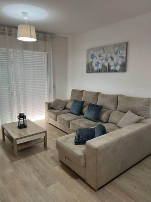A modern living room with a beige sofa, a wooden coffee table, and a painting of flowers on the wall.