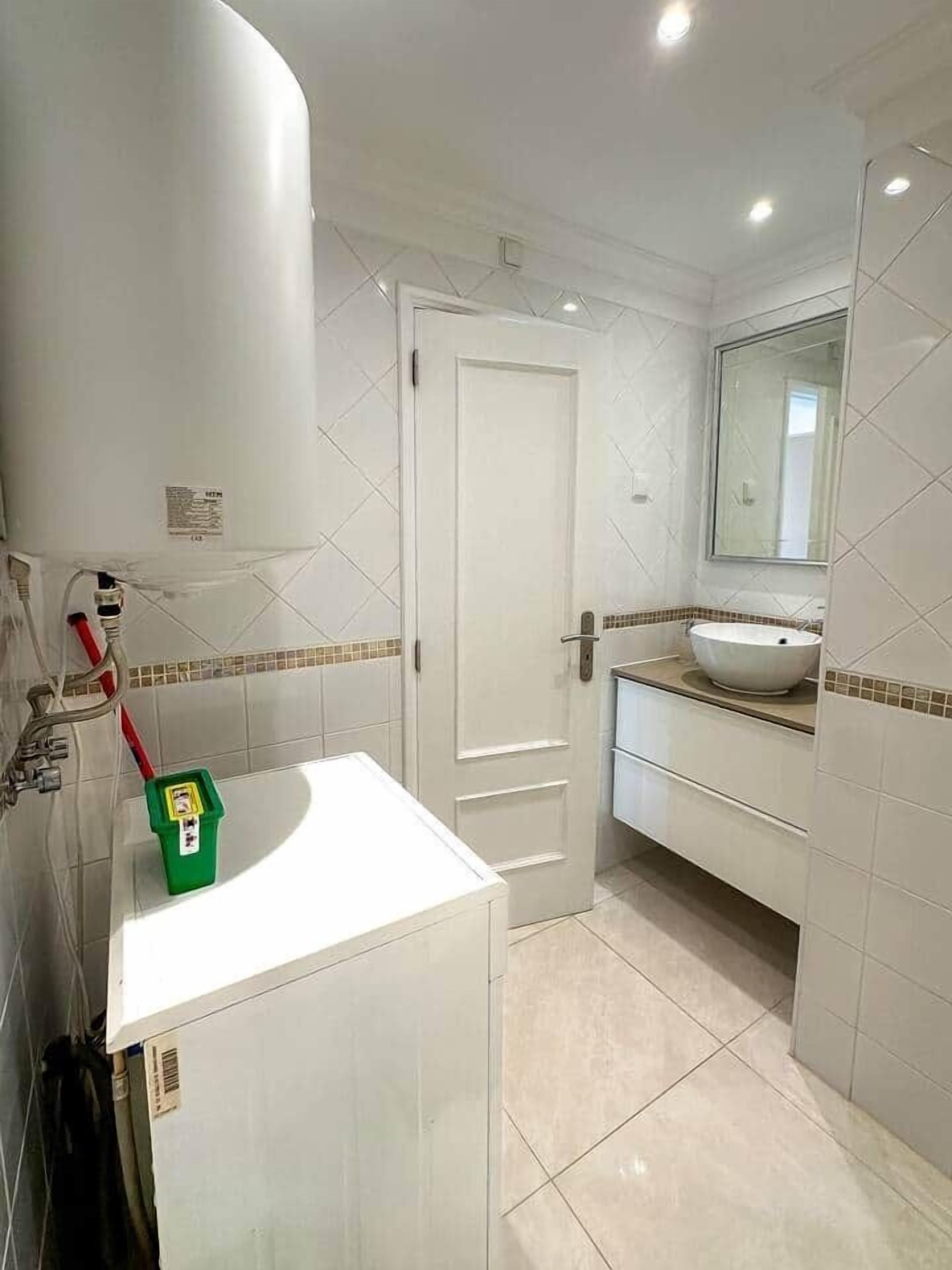 A bathroom with a white sink, a mirror, and a door.