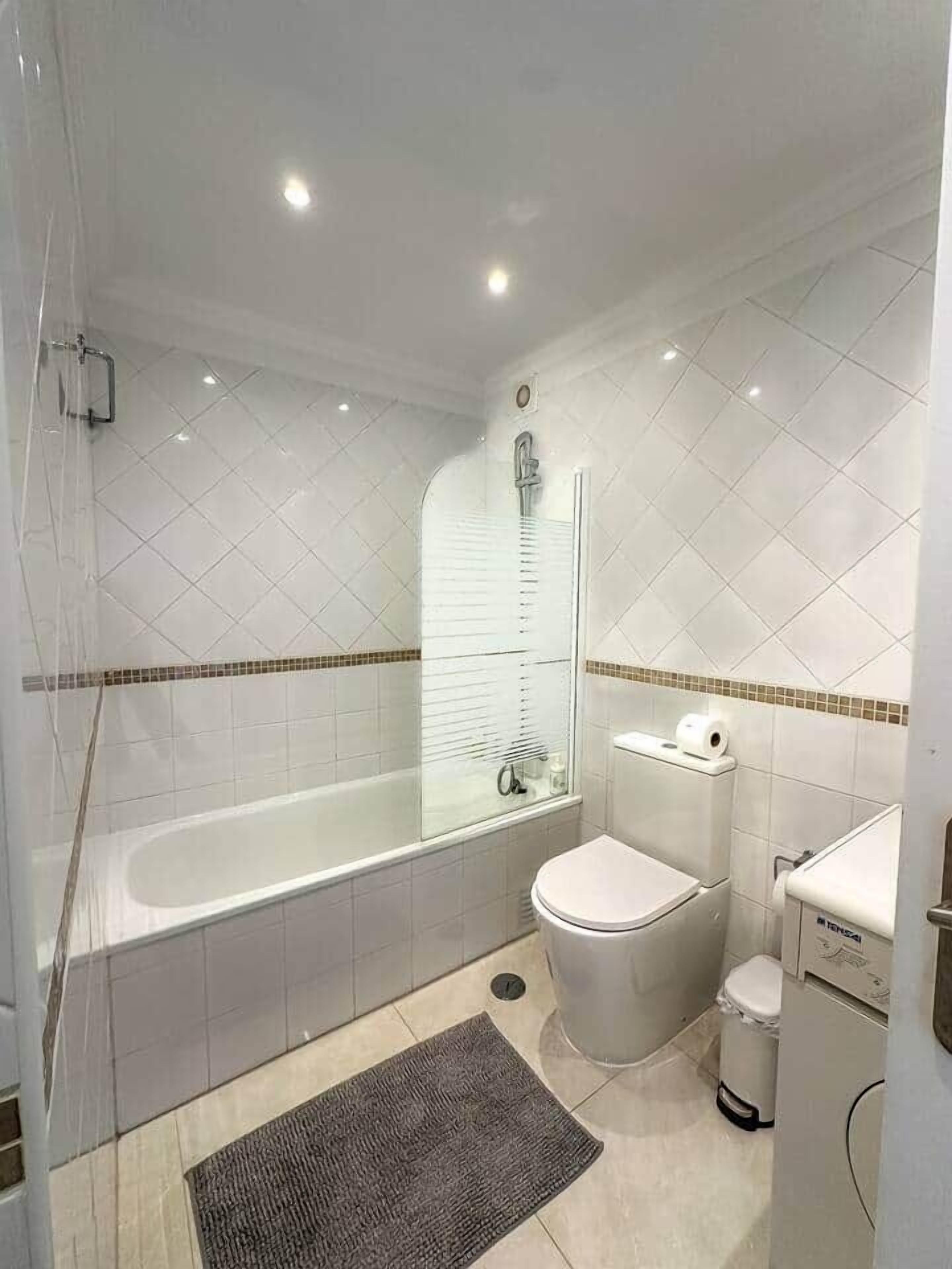 Une salle de bain avec une baignoire, des toilettes et une petite poubelle.