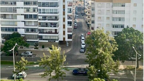 A multi-story residential building with a street in front. - Minimalist Nomad Seaside Apartment (Quarteira)