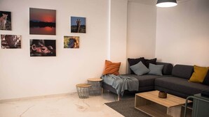 A modern living room with a sectional sofa, a coffee table, and a fireplace. There are framed pictures on the wall and a small round table. - Seaside Inspire Wilderness (Quarteira)