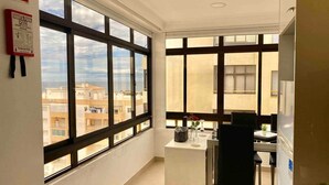 A modern apartment with large windows, a kitchenette, and a dining area. - Rooftop Sea View Apartment (Quarteira)
