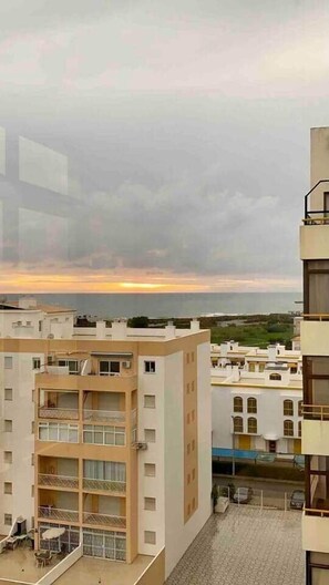 A multi-story residential building with balconies and a view of the sea at sunset. - Rooftop Sea View Apartment (Quarteira)
