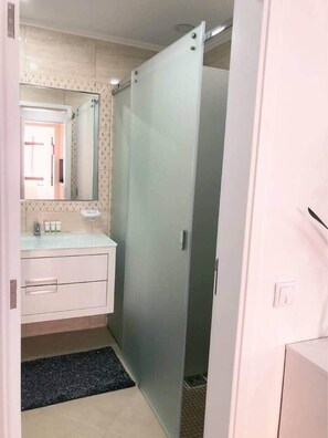 A bathroom with a white vanity, a mirror, and a shower area. - Rooftop Sea View Apartment (Quarteira)