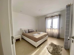 A bedroom with a bed, bedside table, and a rug. - Rooftop Sea View Apartment (Quarteira)