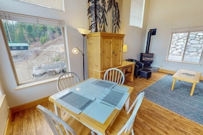 A cozy room with a dining table, chairs, a wooden cabinet, a fireplace, and a view of the outdoors.