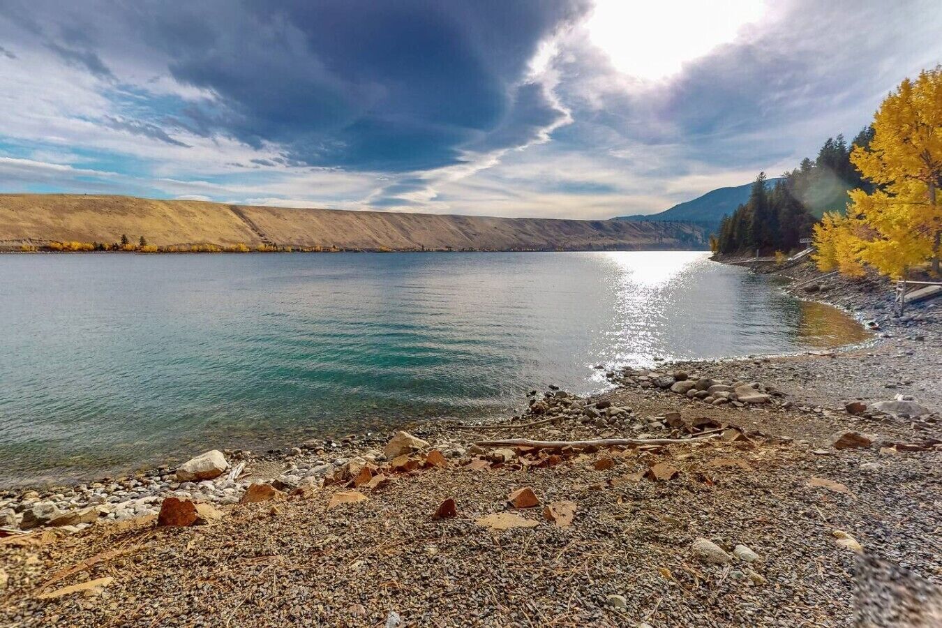 Un lac aux rives rocheuses, avec des arbres en arrière-plan.