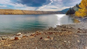 A lake with a rocky shoreline and trees in the background.