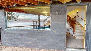 A wooden cabin with a large window, a staircase, and a deck. - The Treehouse lakefront– scenic family getaway (Joseph)