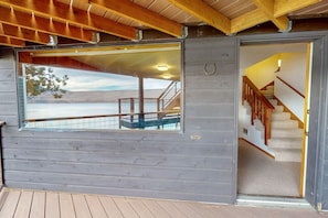 Una cabaña de madera con un ventanal grande, una escalera y una terraza.