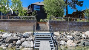 A wooden dock leading to a house with a balcony, surrounded by rocks and clear water. - The Treehouse lakefront– scenic family getaway (Joseph)