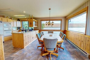 Een moderne keuken met houten kastjes, een centraal eiland en een eethoek met een grote tafel en stoelen.