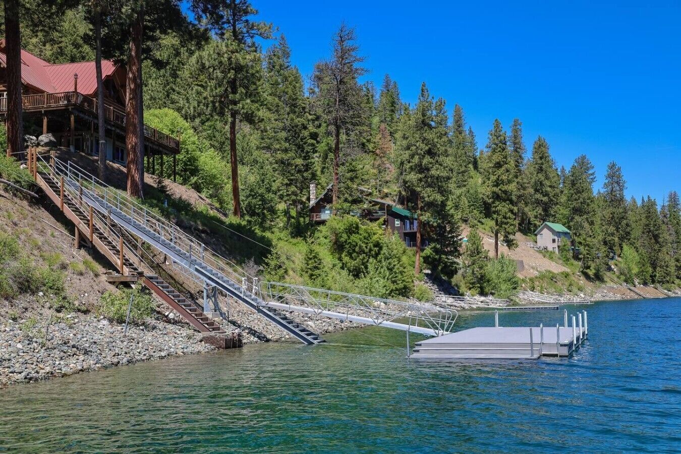 Un chalet au bord du lac, avec un escalier en bois menant à un quai.