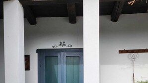 Une entrée d’immeuble avec une porte bleu foncé, un petit vase avec des fleurs et une clôture noire à piquets.