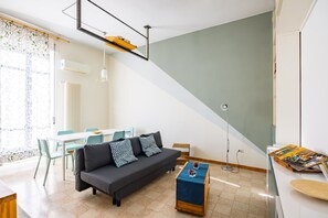A modern living room with a sofa, coffee table, and dining area. - Oasis Flat near San Gregorio Armeno (Naples)