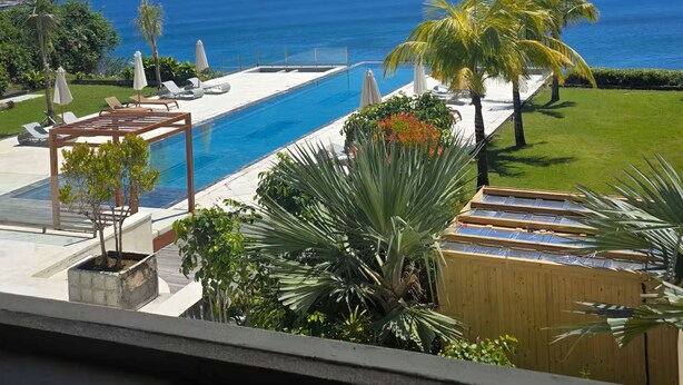 A poolside view with a clear blue sky, a pool, and a view of the ocean. - Villa Anugrah (Badung)