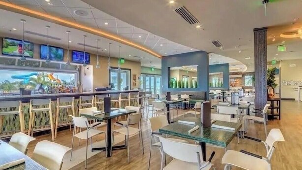 A modern restaurant with a bar area, multiple seating options, and large windows. - Encore 5‑BR Home w/ Private Pool & Spa (Kissimmee)