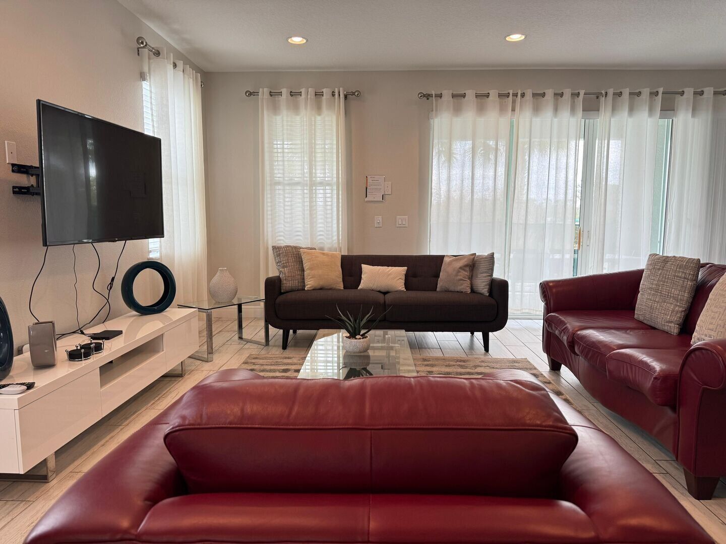 Una sala de estar con sofá, un diván rojo, televisor y mesa de centro.
