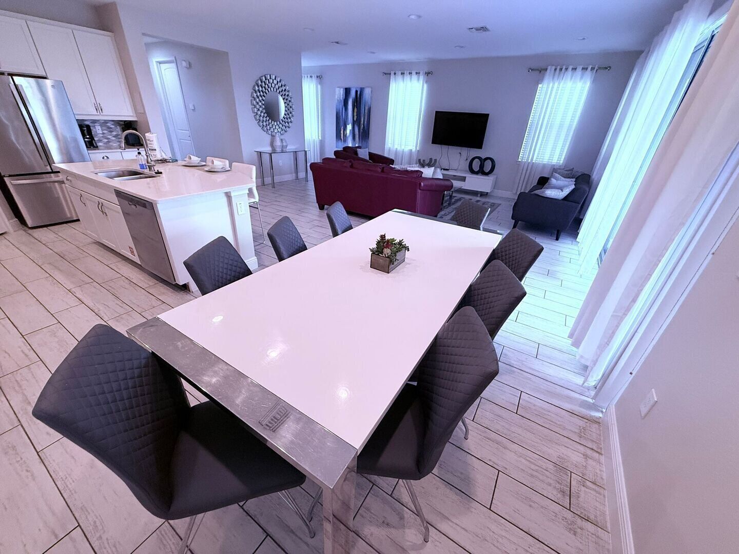 A modern apartment with a dining area, kitchen, living room, and a TV.