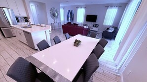 A modern apartment with a dining area, kitchen, living room, and a TV. - Encore 5‑BR Home w/ Private Pool & Spa (Kissimmee)