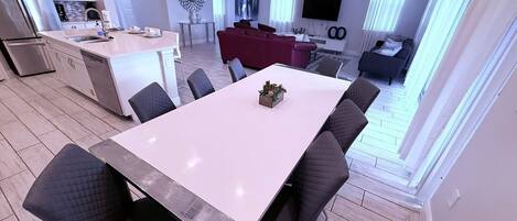 A modern apartment with a dining area, kitchen, living room, and a TV.