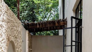 Un área de piscina con un muro de piedra, una pérgola de madera y una cesta negra con frutas.