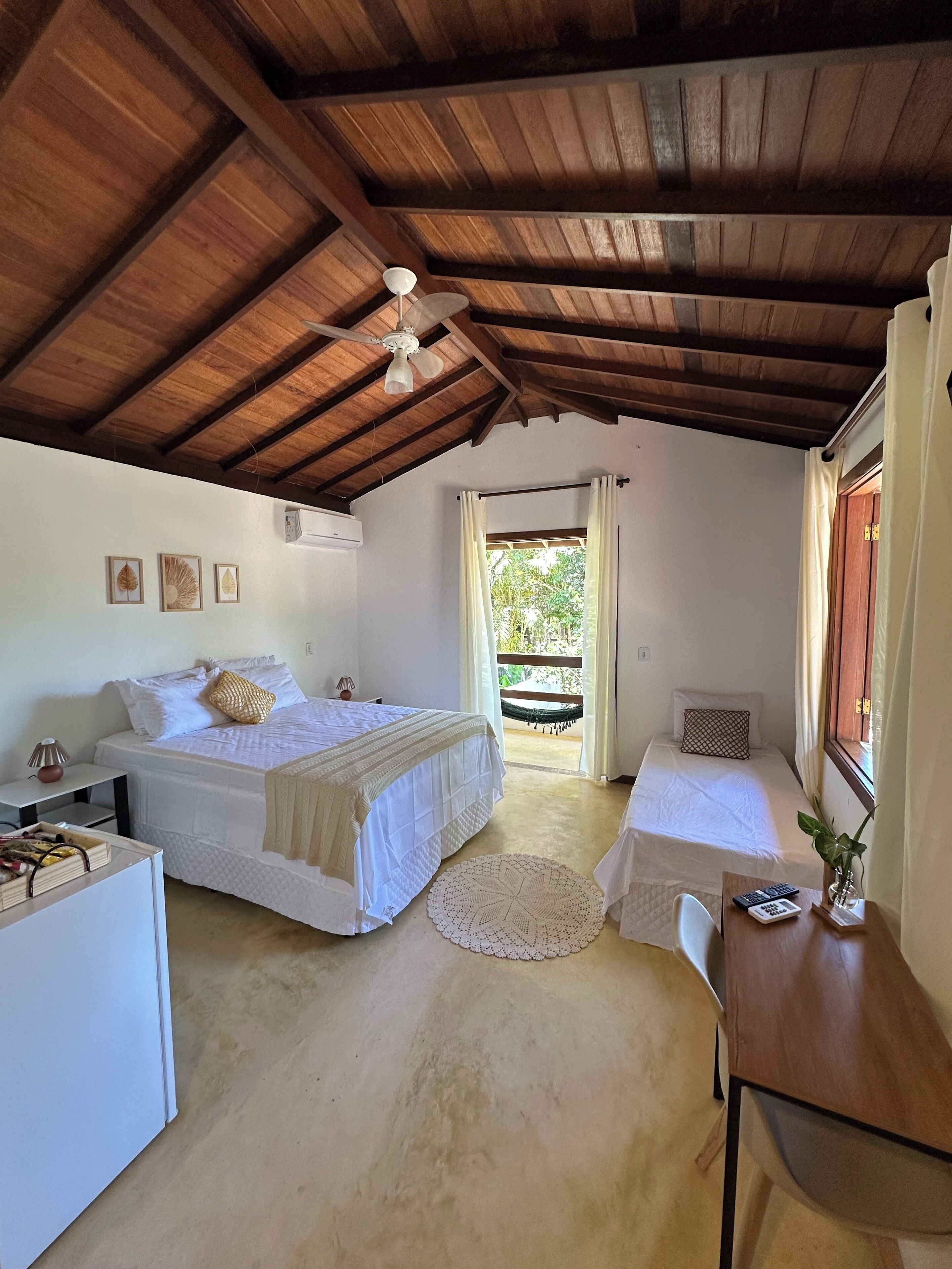 A cozy room with two beds, a ceiling fan, a small table, and a window with curtains.