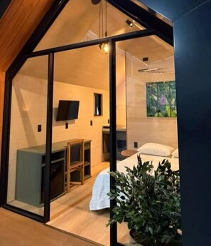 A modern interior with a bed, a desk, and a television. - Pousada ViniCarmel (Porto Seguro)