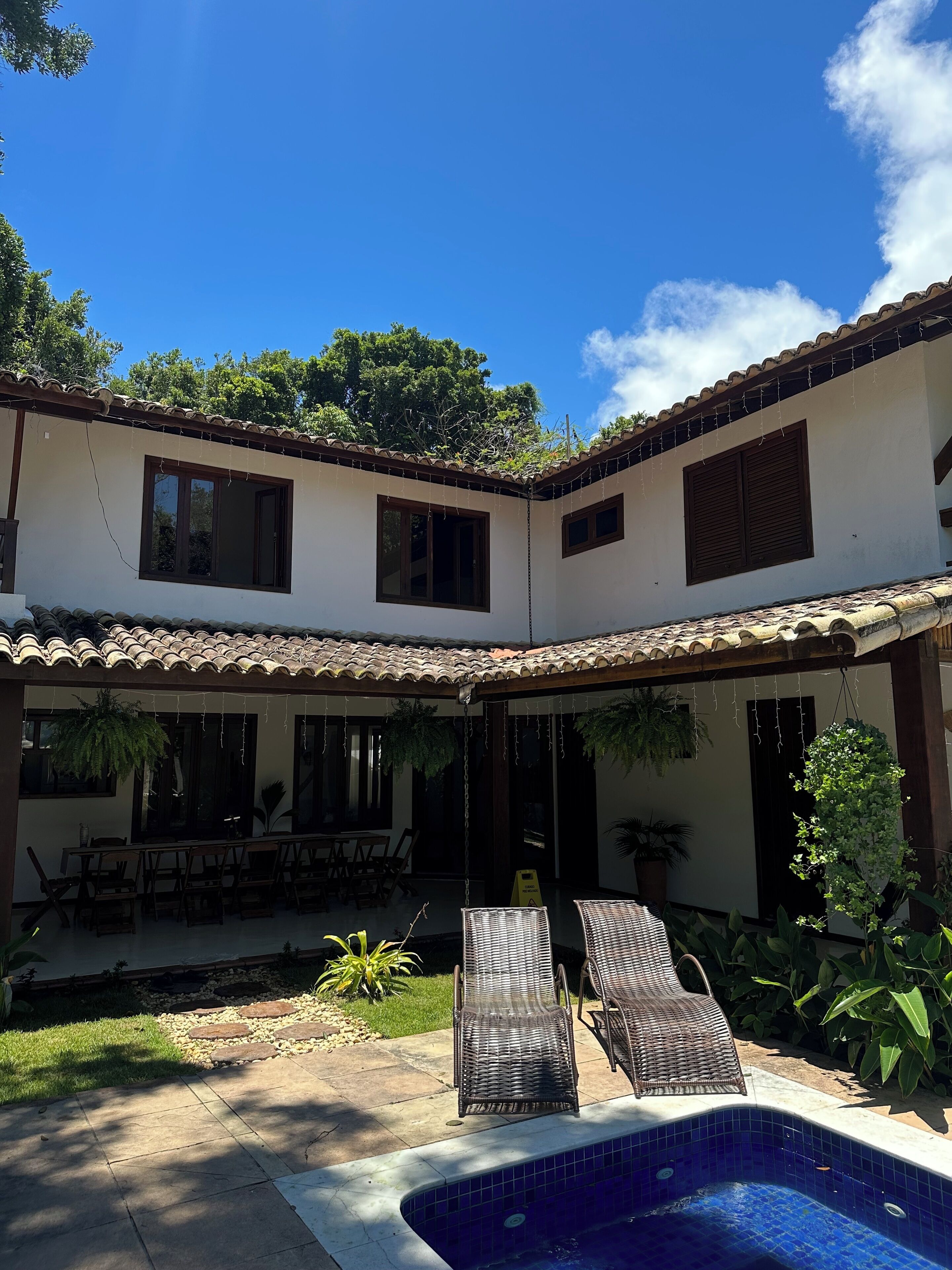 A two-story building with a patio area, outdoor seating, and a swimming pool.